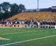 Group of young female athletes forming a line on a sports field, promoting teamwork and community spirit.