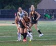 Field hockey players engage in a competitive match, focusing on the ball on a turf field during a spirited game.