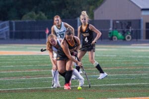 Field hockey players engage in a competitive match, focusing on the ball on a turf field during a spirited game.