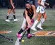A field hockey player in action, skillfully maneuvering the ball on the turf during a competitive match.