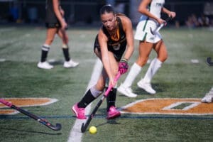 A field hockey player in action, skillfully maneuvering the ball on the turf during a competitive match.