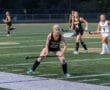 Field hockey players in action during a game on a well-maintained turf field, showcasing teamwork and athleticism.