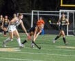 Field hockey players compete during a night match, showcasing action and teamwork on the field.