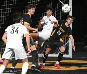 High school soccer players compete for the ball in a thrilling match, showcasing athleticism and teamwork.