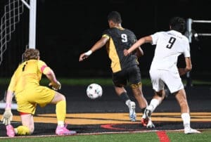 Soccer players compete for the ball near the goal during a night match, showcasing athleticism and teamwork.