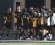 High school soccer team celebrating a goal under stadium lights, showcasing teamwork and excitement on the field.
