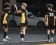 Three soccer players celebrate on the field, showcasing team spirit and camaraderie during a nighttime match.